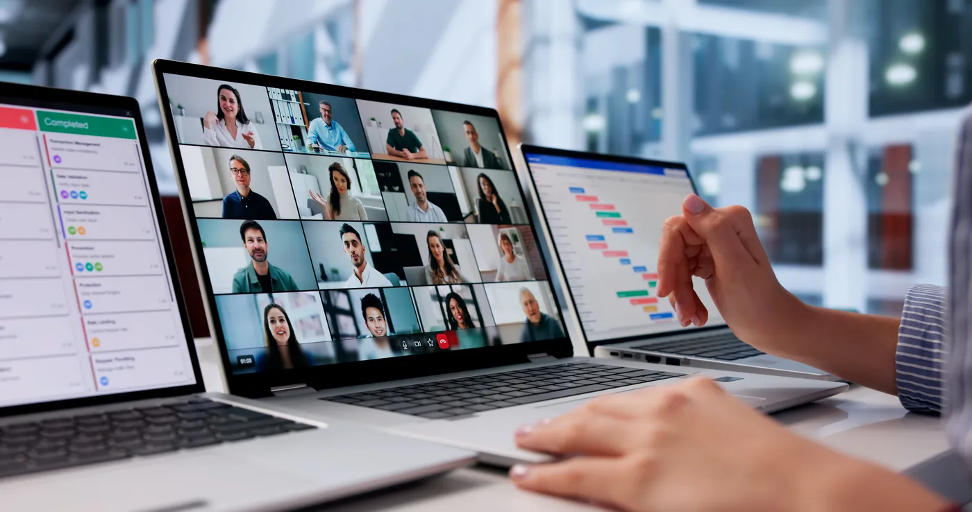 A webinar participant using laptops to join a video discussion and review event information.